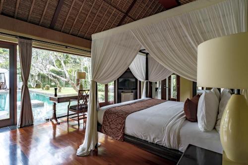 1 dormitorio con cama con dosel y piscina en Kayumanis Nusa Dua Private Villa & Spa en Nusa Dua