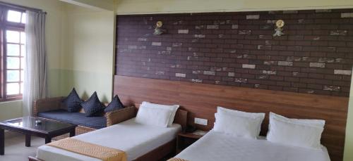 a room with two beds and a couch and a brick wall at Apsara Guest House in Shillong