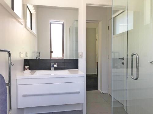 uma casa de banho com um lavatório e uma cabina de duche em vidro. em The Garden Studio - Queenstown em Queenstown