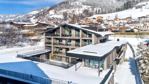 a house in the snow with mountains in the background at Emma Deluxe Aparthotel ganzjährig beheizter Außenpool in Piesendorf