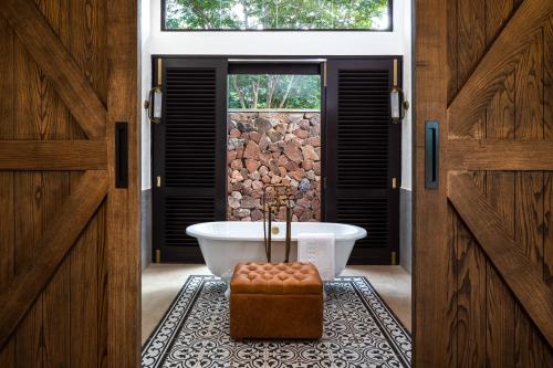 a bathroom with a bath tub and a window at Mbano Manor Hotel Victoria Falls in Victoria Falls