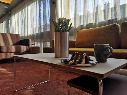 a table with a plate of cake and a vase at Edinburgh Central Accommodation in Edinburgh