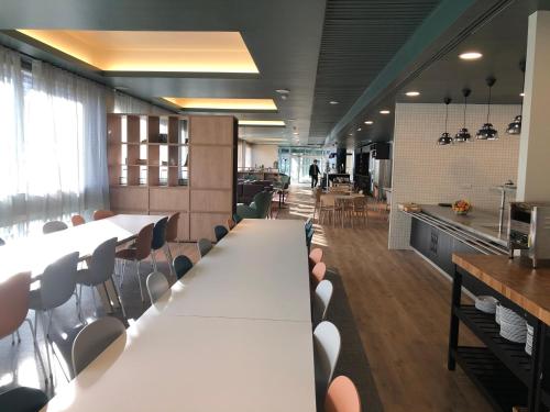 a cafeteria with white tables and chairs and a kitchen at Edinburgh Central Accommodation in Edinburgh