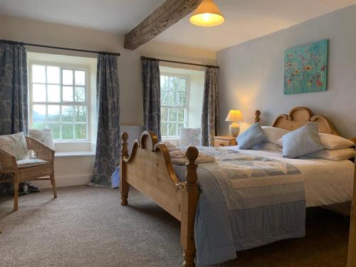 una camera con un grande letto e due finestre di Witherslack Hall Farmhouse a Grange Over Sands