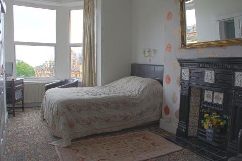 a bedroom with a bed and a fireplace and a mirror at Ashfield Guesthouse in Douglas