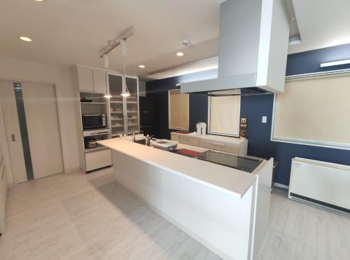 uma grande cozinha com armários brancos e uma bancada em Private House Naturwald em Furano