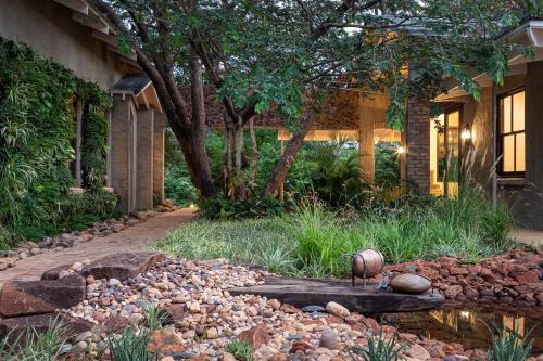 a garden with a pond in front of a house at Mbano Manor Hotel Victoria Falls in Victoria Falls