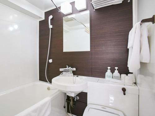 a bathroom with a sink and a toilet and a mirror at Kanku Sun Plus Yutaka in Izumi-Sano