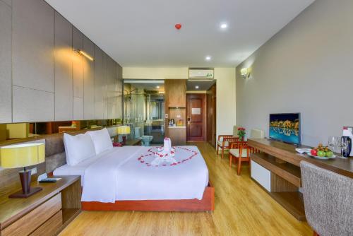 a bedroom with a large white bed and a kitchen at MANLI Resort Quảng Bình in Dong Hoi