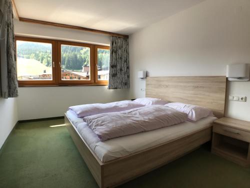 ein Schlafzimmer mit einem großen Bett und einem großen Fenster in der Unterkunft Appartements Robert - Hotel Bechlwirt in Kirchberg in Tirol