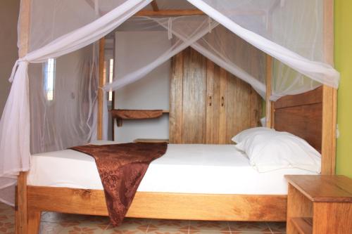 a bedroom with a wooden bed with a canopy at Africa 6 Plage in Somone
