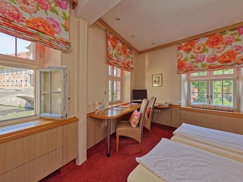 a bedroom with two beds and a table and a desk at Hotel Brudermühle in Bamberg