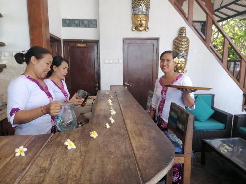 a group of three women standing around a table at Puri Oka Beach Bungalows in Candidasa