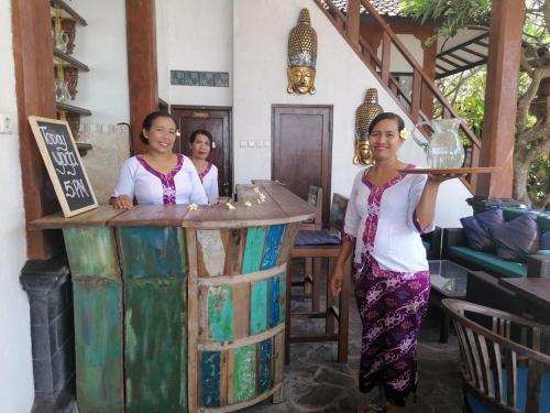 three women standing at a bar with a glass at Puri Oka Beach Bungalows in Candidasa