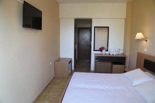 a bedroom with a bed and a desk and a television at Rhodian Sun Hotel in Paradeísion