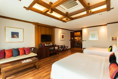 a hotel room with two beds and a couch at Phra Singh Village in Chiang Mai