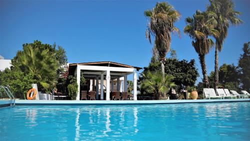 a swimming pool in front of a house with palm trees at Rhodian Sun Hotel in Paradeísion