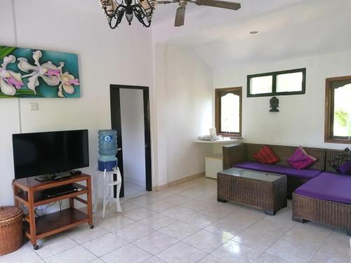 a living room with a couch and a tv at Puri Oka Beach Bungalows in Candidasa