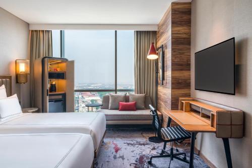 a hotel room with a bed and a desk and a couch at Swissôtel Jakarta PIK Avenue in Jakarta
