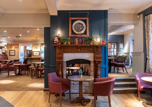 a lobby with a fireplace and tables and chairs at Toby Carvery Old Windsor by Innkeeper's Collection in Windsor