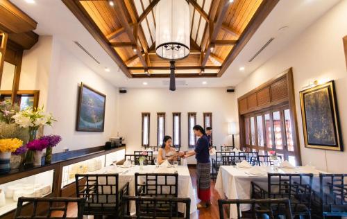 two people standing in a dining room with tables at Phra Singh Village in Chiang Mai