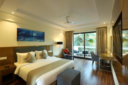 a hotel room with a large bed and a desk at Resort The Lohias, Goa Candolim in Candolim