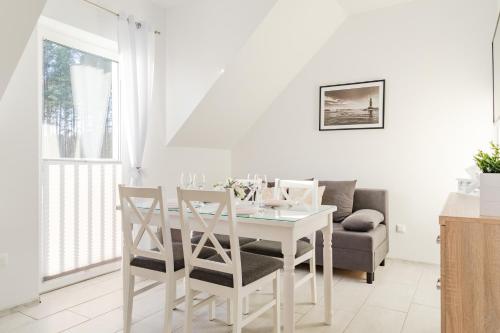 a white dining room with a white table and chairs at Nadmorska Przystan - Apartamenty caloroczne in Ustka