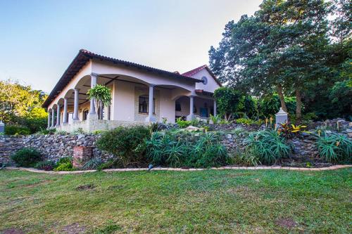 a house with a stone wall and a yard at Stephan's Guest House in Port Shepstone