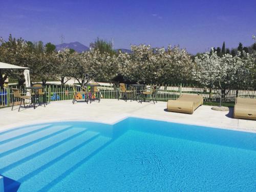 a blue swimming pool with chairs and tables and trees at Agriturismo & Agricamping Serena in Pastrengo