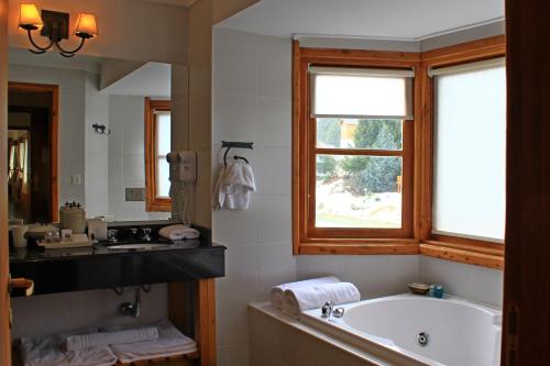 baño con bañera, lavabo y ventana en Club Hotel Catedral en San Carlos de Bariloche