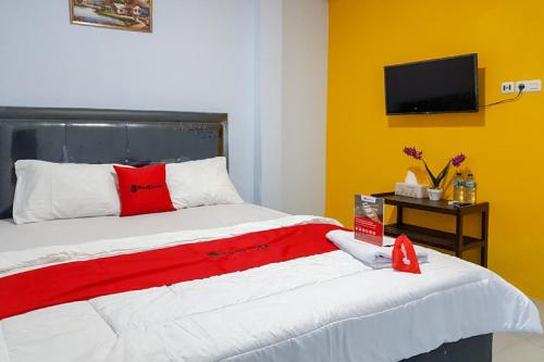 a bedroom with a bed with a red and white blanket at RedDoorz near RSUD Kota Luwuk in Luwuk