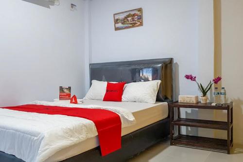 a bedroom with a large bed with a red blanket at RedDoorz near RSUD Kota Luwuk in Luwuk