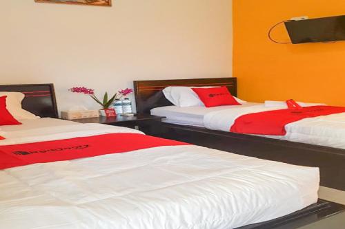 a bedroom with two beds with red and white sheets at RedDoorz near RSUD Kota Luwuk in Luwuk
