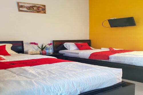 a bedroom with two beds with red and white sheets at RedDoorz near RSUD Kota Luwuk in Luwuk