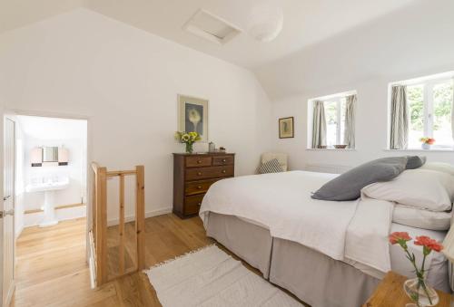 a white bedroom with a bed and a dresser at Little Winters Cottage in Lyme Regis