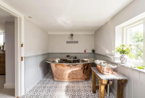 baño con bañera de cobre y lavamanos en Lanes End Cottage en Dorchester