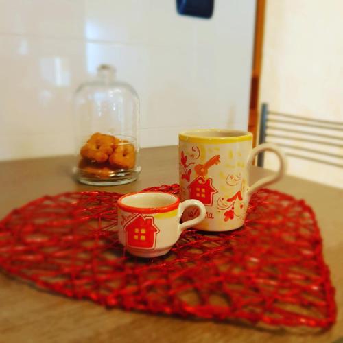 two coffee cups sitting on a table with a red blanket at La Casa di Ninna Affittacamere in Ariano Irpino