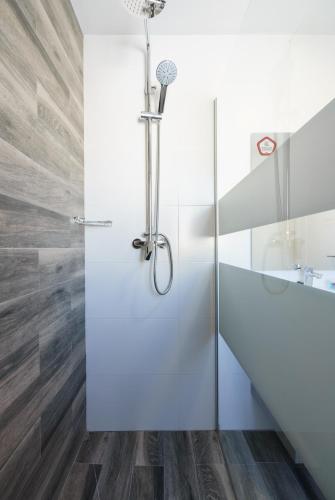 a shower in a bathroom with white walls and wood floors at Hotel El Ancla in Calahonda