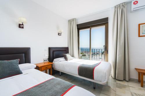 a hotel room with two beds and a window at Hotel El Ancla in Calahonda