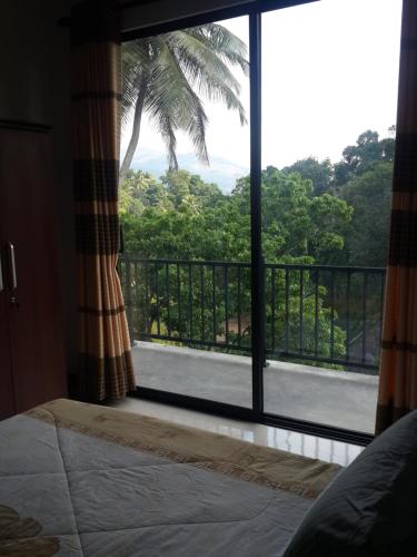 een kamer met een groot raam met uitzicht op een balkon bij Hanthana view in Peradeniya