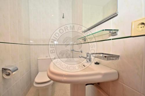 a bathroom with a sink and a toilet and a mirror at Apartamentos Paraíso Centro - BenidormParaíso in Benidorm