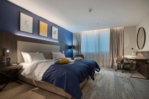 una camera da letto con un letto grande con una parete blu di voco - Podgorica by IHG a Podgorica