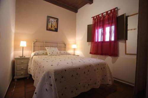 1 dormitorio con cama y ventana roja en Las Casitas en Higuera de la Sierra