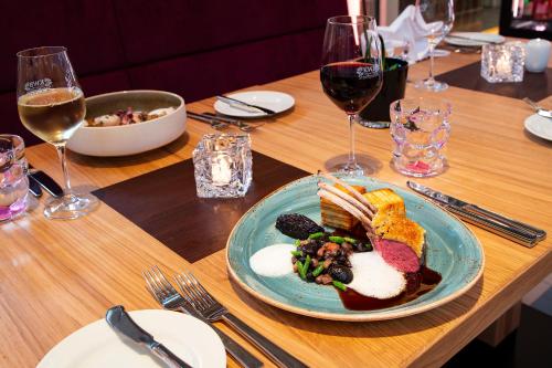 a table with a plate of food and glasses of wine at Hotel Stadtpalais in Cologne