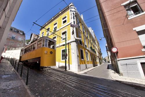 a yellow streetcar on a city street with a yellow building at TURIM Restauradores Hotel in Lisbon