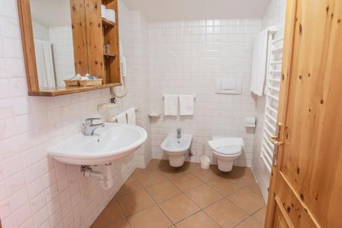 a white bathroom with a sink and a toilet at Sporting Clubresidence in San Martino di Castrozza