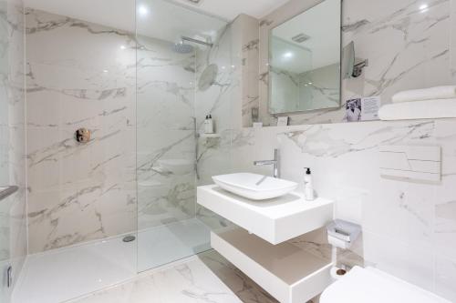 a white bathroom with a sink and a shower at Palm Court Hotel in Aberdeen