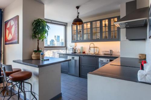 a kitchen with blue cabinets and a large window at Le « 24th » on Blum Square in Puteaux