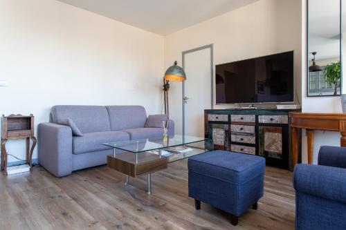 a living room with a couch and a tv at Le « 24th » on Blum Square in Puteaux