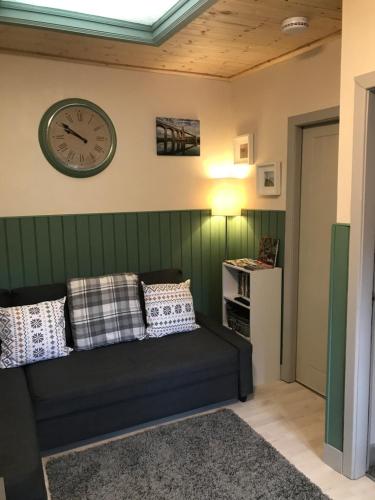 a living room with a couch and a clock on the wall at Apartment/Flat 3 in Menai Bridge